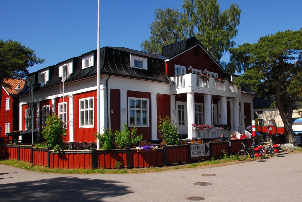 uma casa vermelha e branca com um telhado preto em Hotel Strandbo em Nauvo