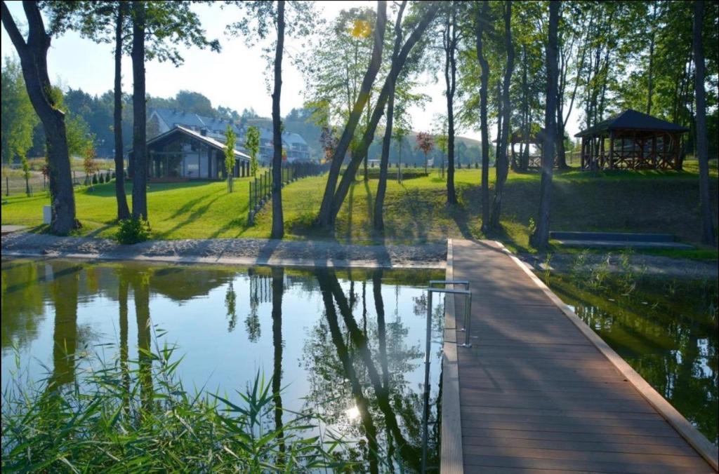 une passerelle en bois dans un parc avec un étang dans l'établissement Mazury Lake View & Ski Appartment, à Mrągowo