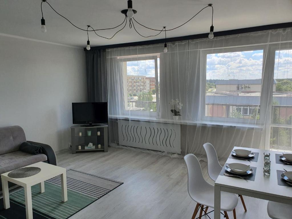 a living room with a table and chairs and two windows at Apartament przy promenadzie in Ełk