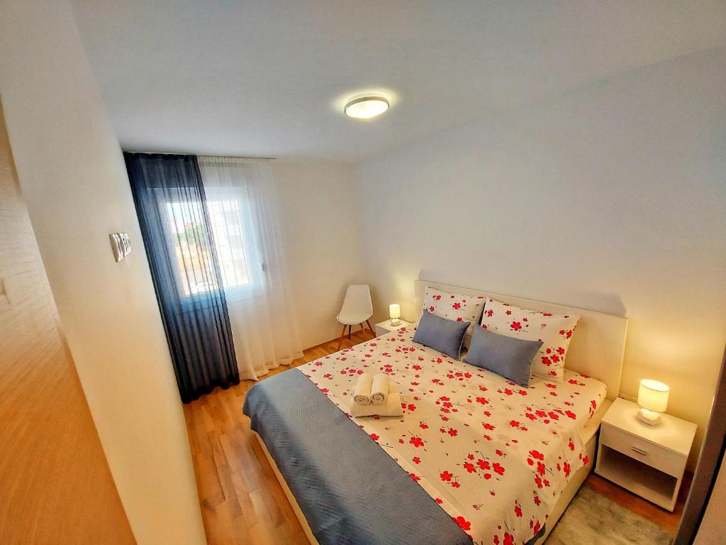 una camera da letto con un letto con fiori rossi di Tusculum apartment Solin a Solin (Salona)