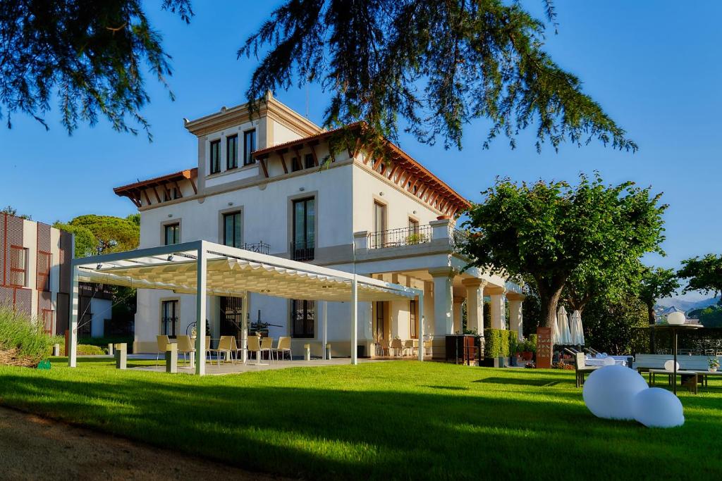 a large white house with a grass yard at Hotel Arrey Alella in Alella