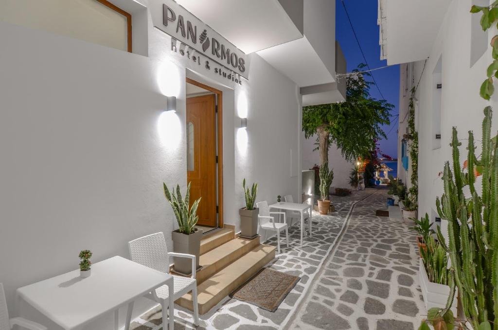 a white building with tables and chairs and plants at Panormos Hotel and Studios in Naxos Chora