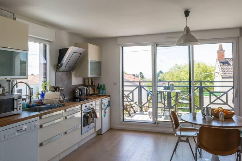 een keuken met een tafel en uitzicht op een balkon bij Proche mer, plage et commerces à 500m in La Bernerie-en-Retz