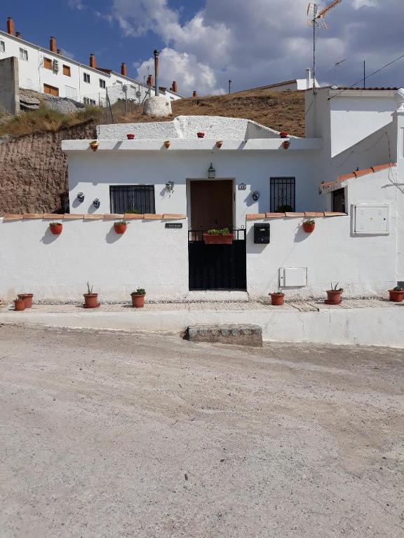a white building with a door on a street at The Welcome Cave in Freila