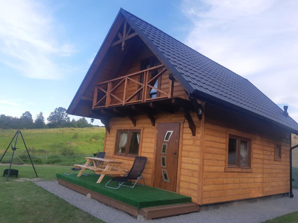 a small wooden cabin with a table and a bench at Domek na wzgórzu "RYŚ" in Krempna