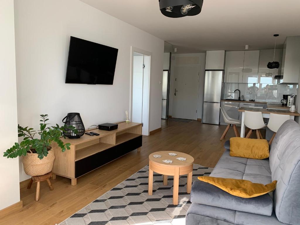 a living room with a couch and a table at Apartament Szmaragdowy Platan in Kołobrzeg