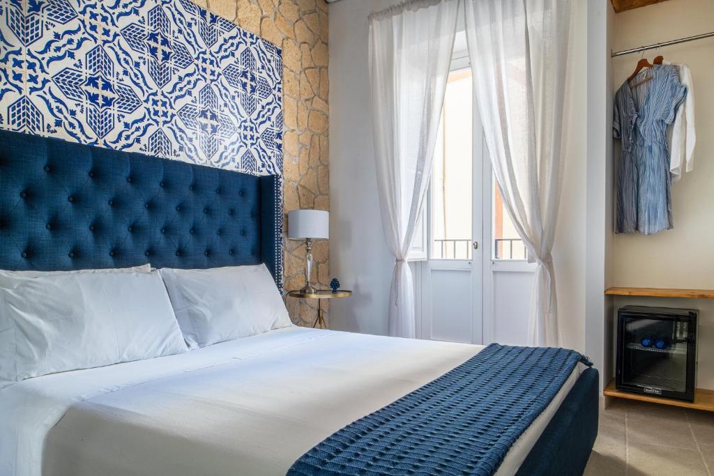 um quarto com uma cama com uma cabeceira azul e uma janela em Incanto Siciliano em Noto