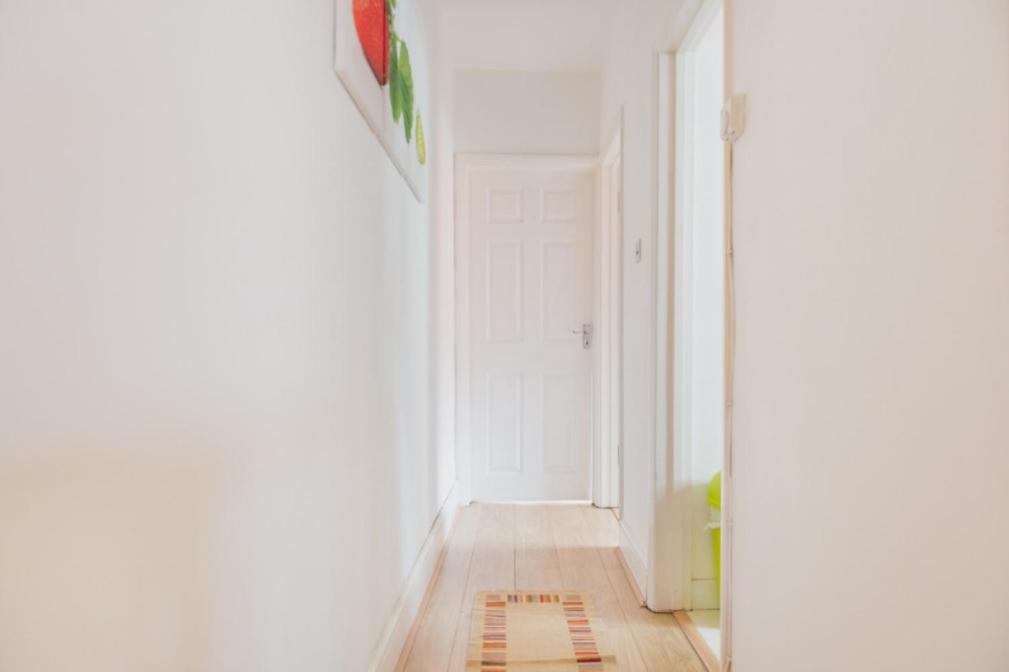 a hallway with a white door and a rug on the floor at 03 Bedroom Apartment-Self Check in in London