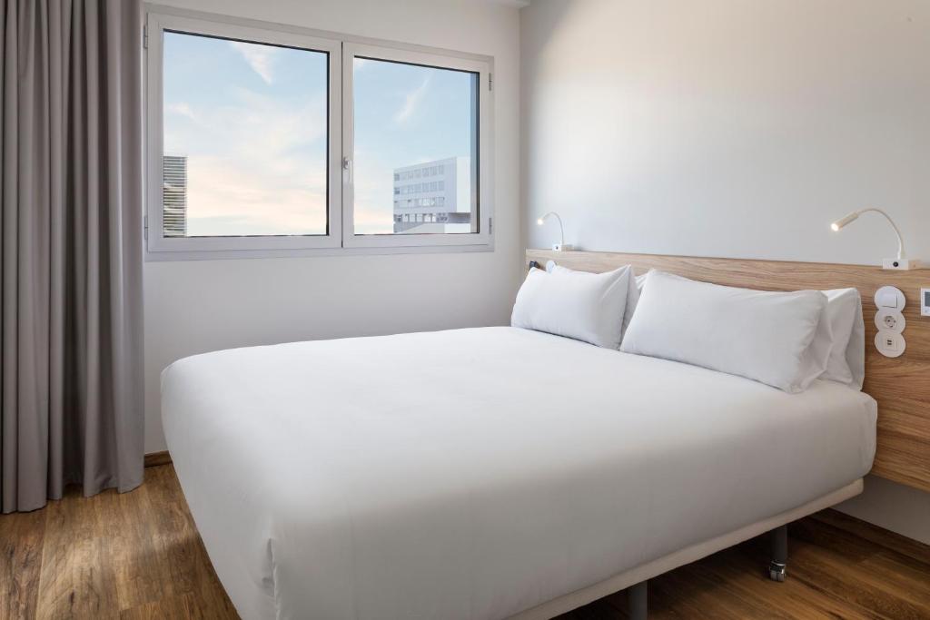 - un lit blanc dans une chambre avec fenêtre dans l'établissement B&B HOTEL Lisboa Aeroporto, à Lisbonne