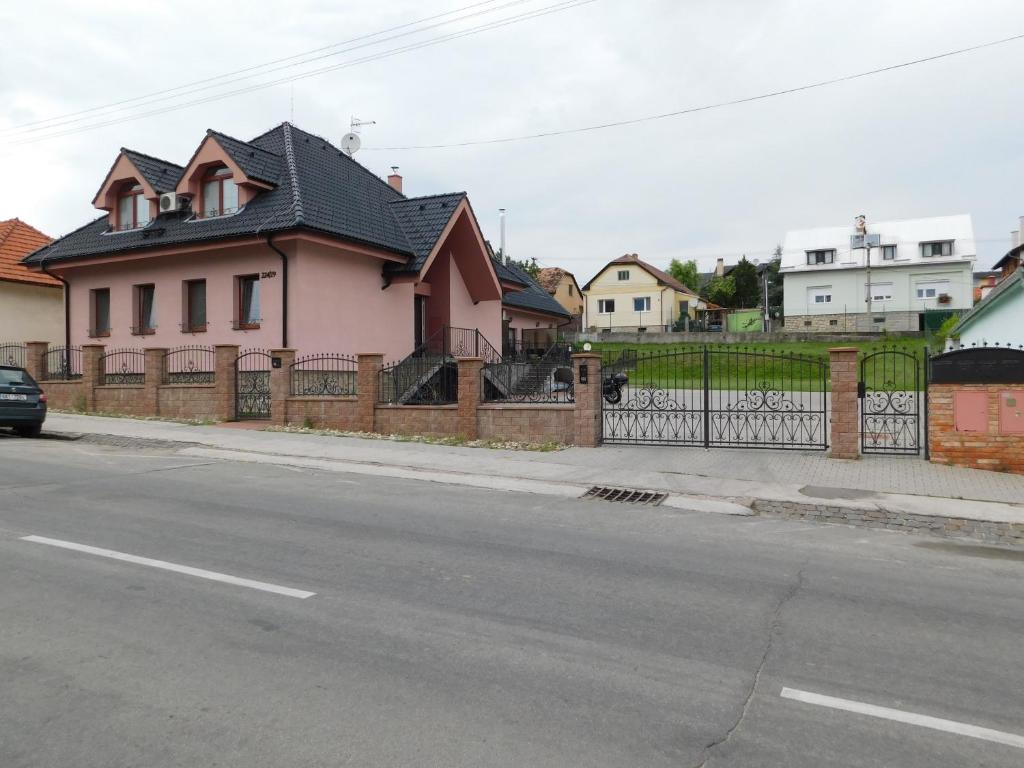 a pink house with a fence on the side of a street at Apartmánový Penzión Bojnice in Bojnice