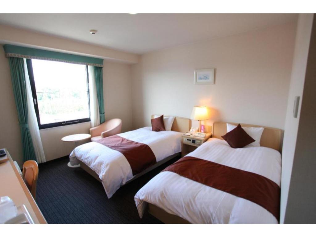Cette chambre comprend 2 lits et une fenêtre. dans l'établissement Hotel Verfort Hyuga - Vacation STAY 88277, à Hyuga
