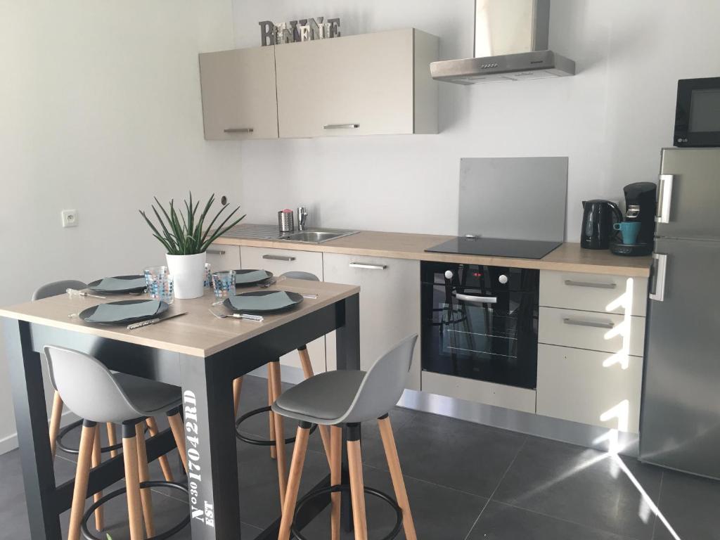 a kitchen with a table and chairs and a refrigerator at Mer et Marais in Colleville-Montgomery