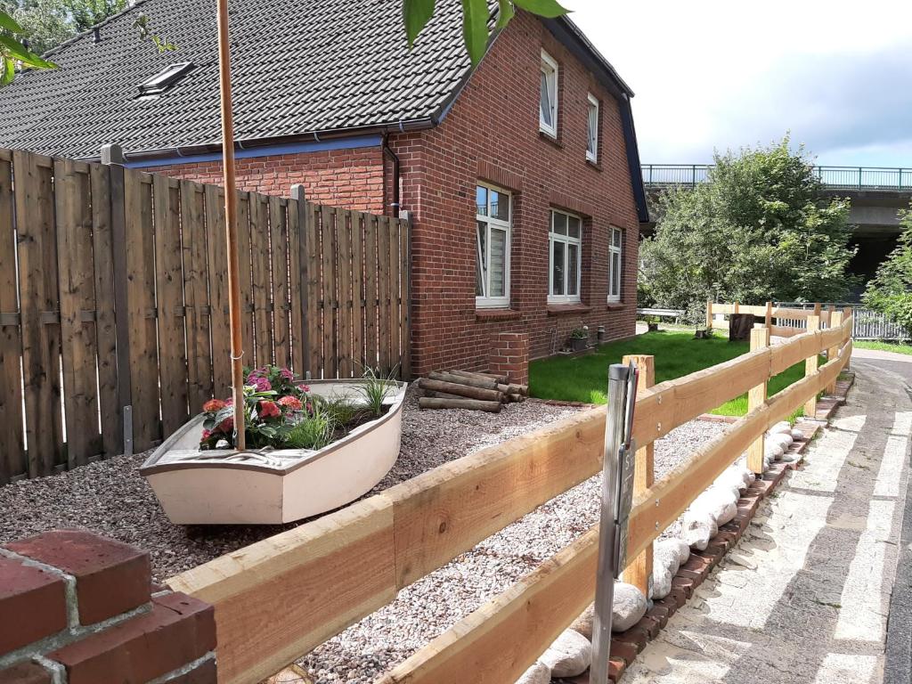 uma casa com uma cerca de madeira e um jardim de flores em Ferienwohnung Herrlichkeit em Neuhaus an der Oste