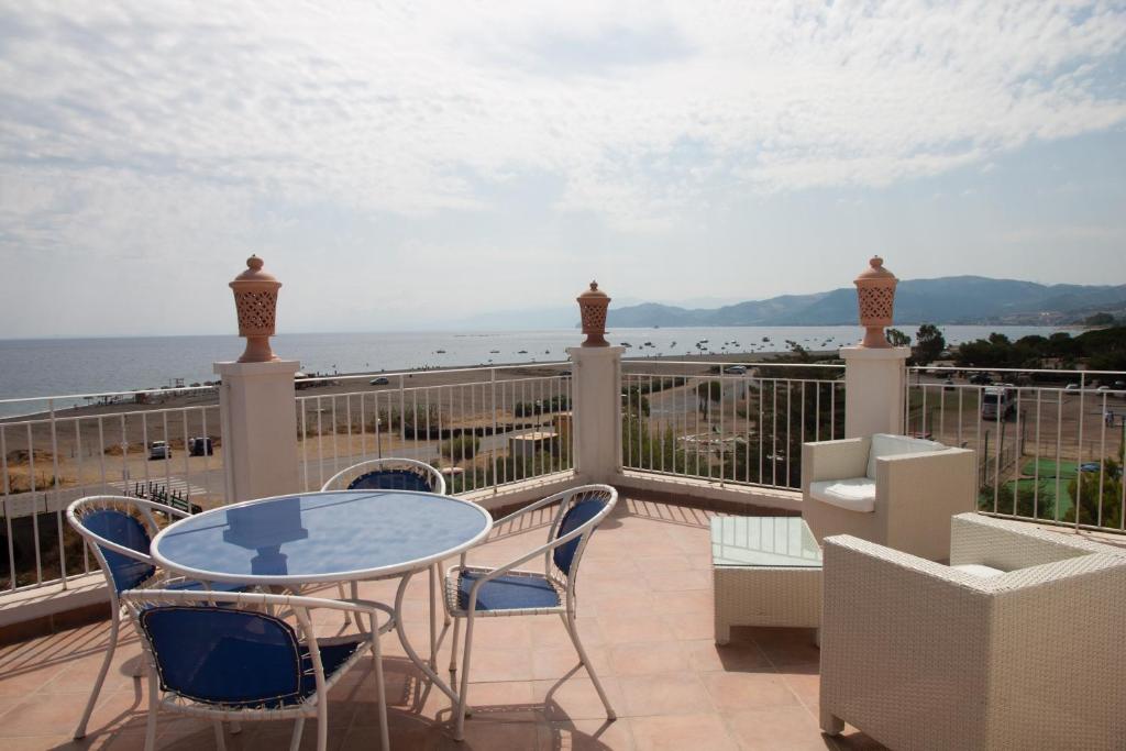 balcón con mesa, sillas y vistas al océano en Yachting Club Mare en Patti
