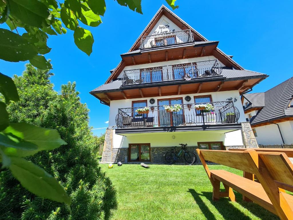 un edificio con balcones y un banco frente a él en Willa Wrzos, en Zakopane