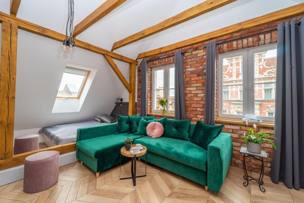 a living room with a green couch and a bed at Boutique Gdańsk Apartments in Gdańsk