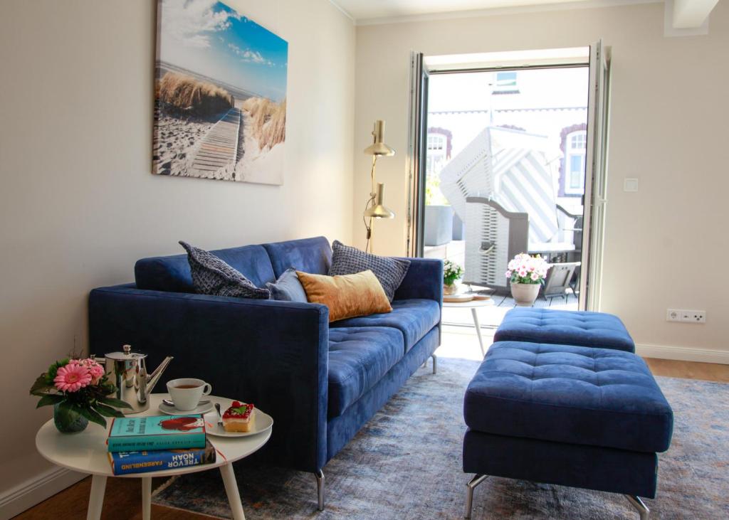 uma sala de estar com um sofá azul e uma mesa em Haus Vier Jahreszeiten em Wangerooge