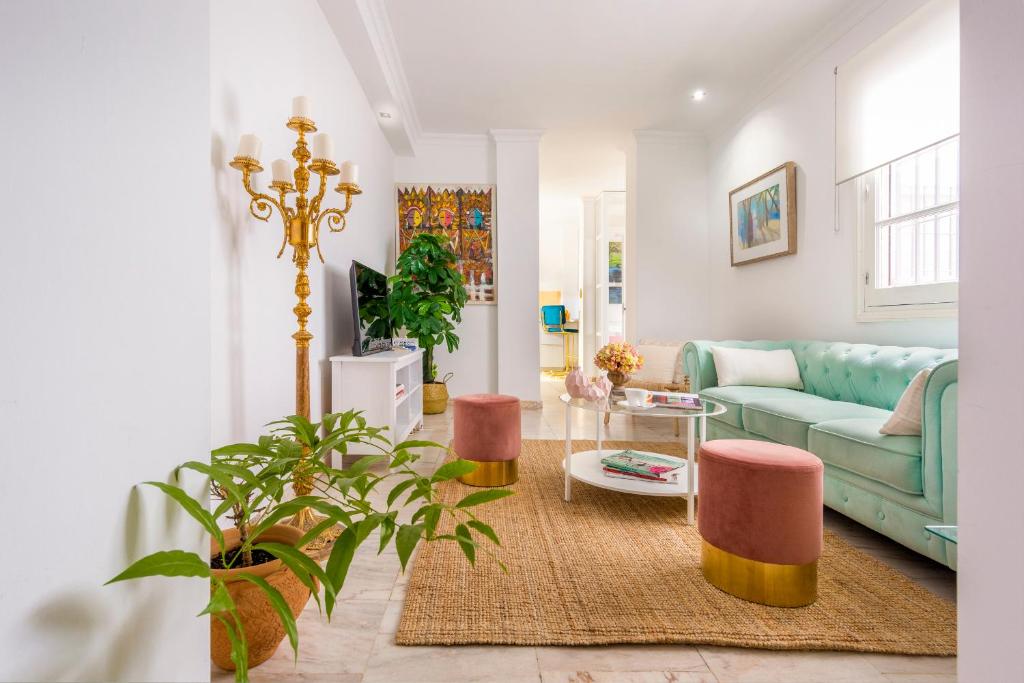 sala de estar con sofá azul y sillas rosas en UNICO ALCAZAR Apartment, en Sevilla