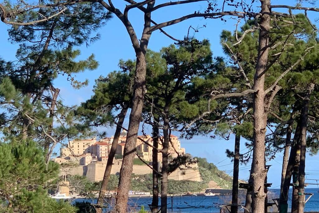 a view of a castle through some trees at Appartement neuf sur Plage de Calvi Vue Mer in Calvi