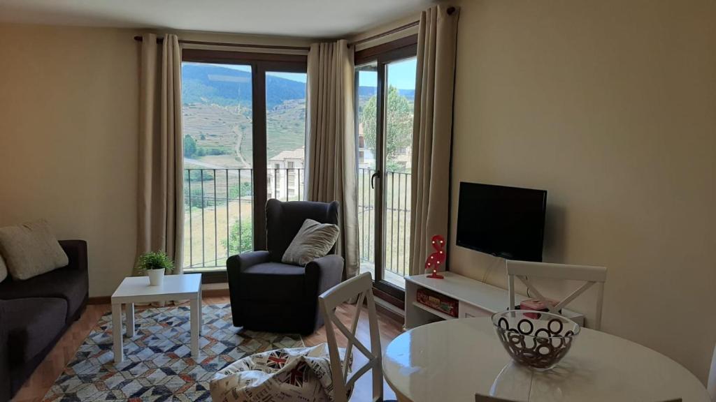 a living room with a couch and a table and a television at Apartamento Las Vistillas in Valdelinares