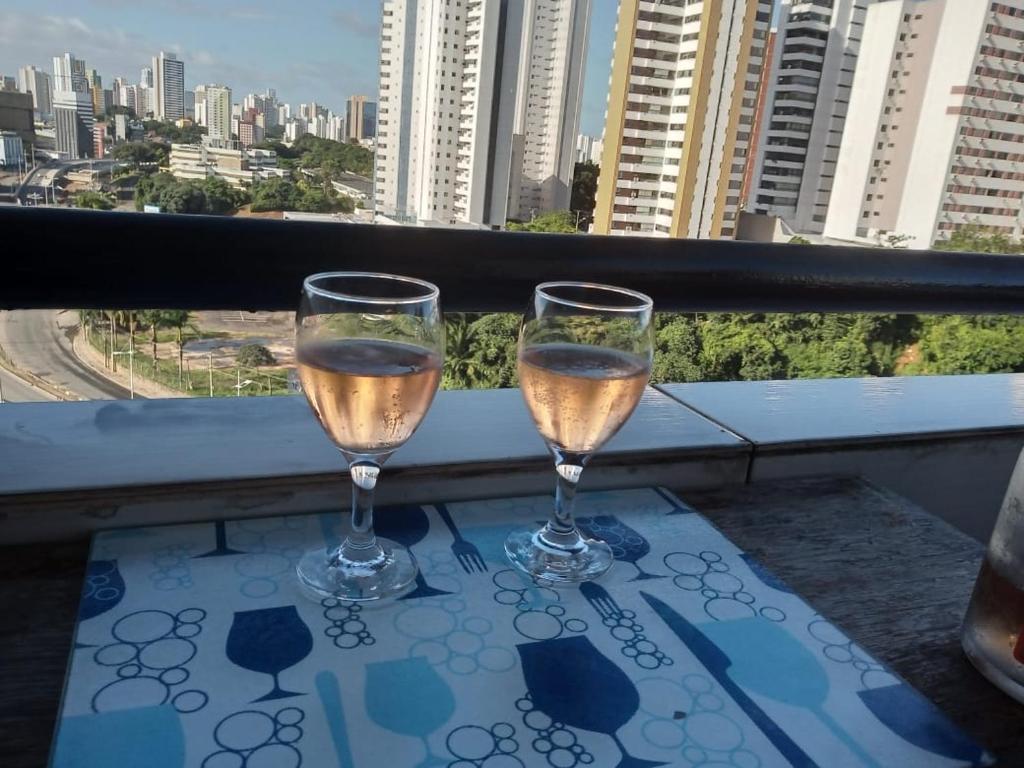 dois copos de vinho sentados numa mesa na varanda em Flat Ana Regis ap1010 em Salvador
