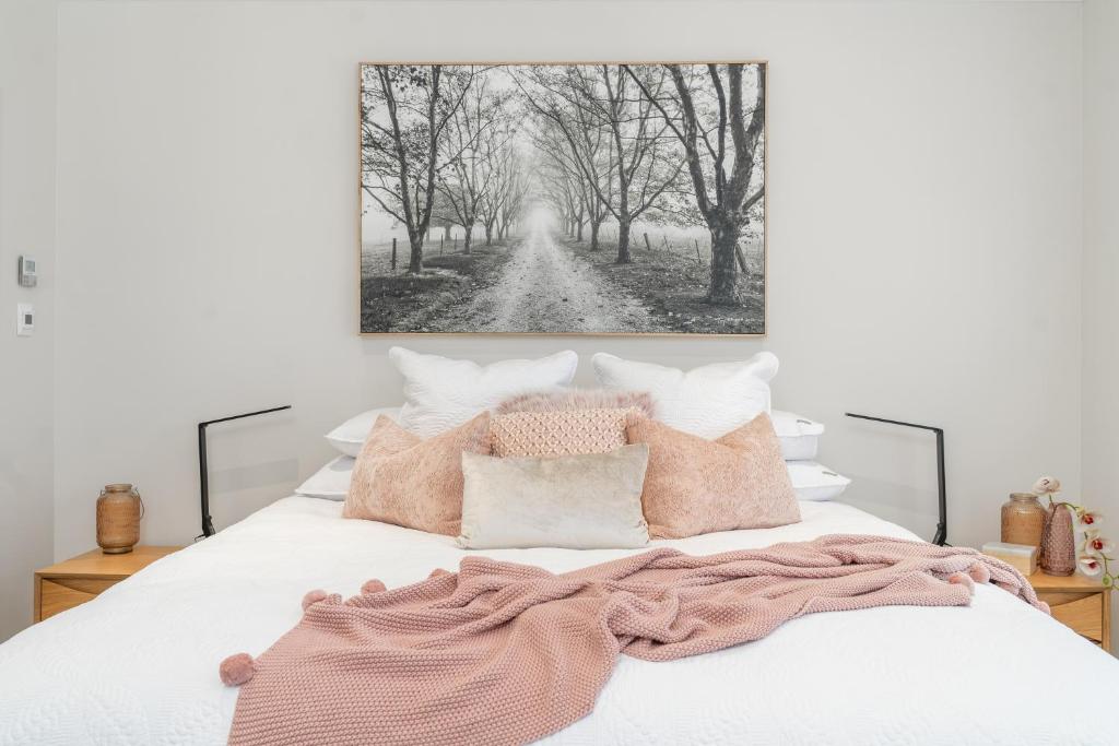 a bed with pink pillows and a painting on the wall at Hall House in Bowral