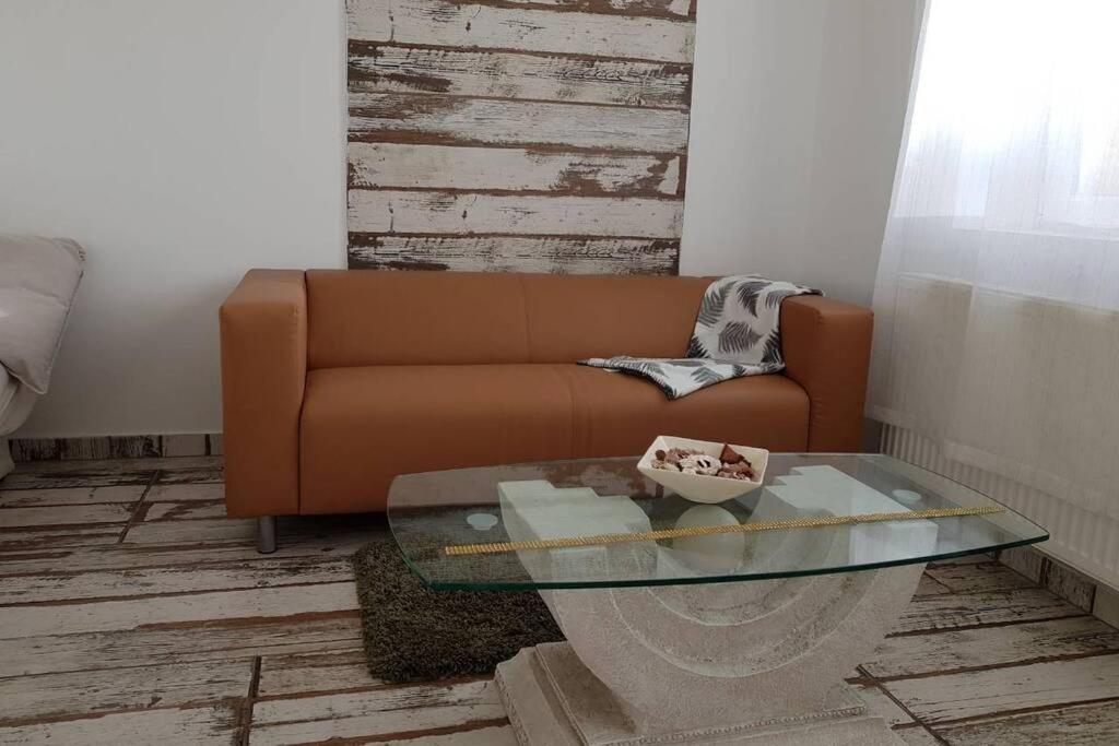 ein Wohnzimmer mit einem Sofa und einem Glastisch in der Unterkunft Cozy apartment in the heart of Kecskemet in Kecskemét