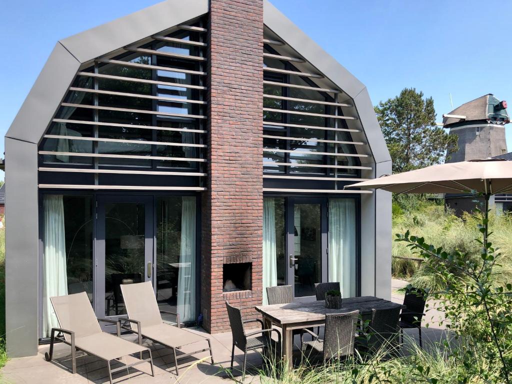 une maison en verre avec une table et des chaises dans l'établissement Villa Klein Geluk, à Egmond aan Zee