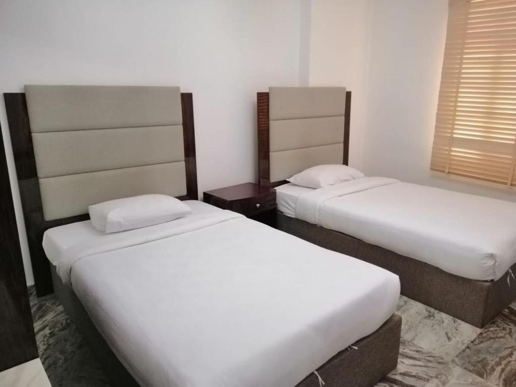 2 letti in camera d'albergo con lenzuola bianche di Royal Suite Hotel Apartments a Al Ḩuwayl