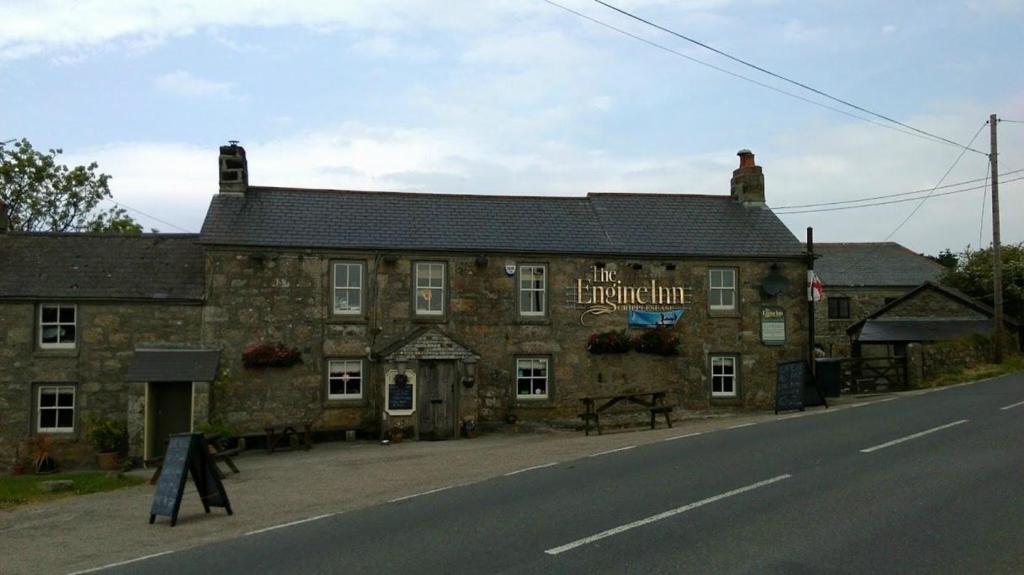 un antiguo edificio de piedra al lado de una carretera en the Engine Inn, en Penzance