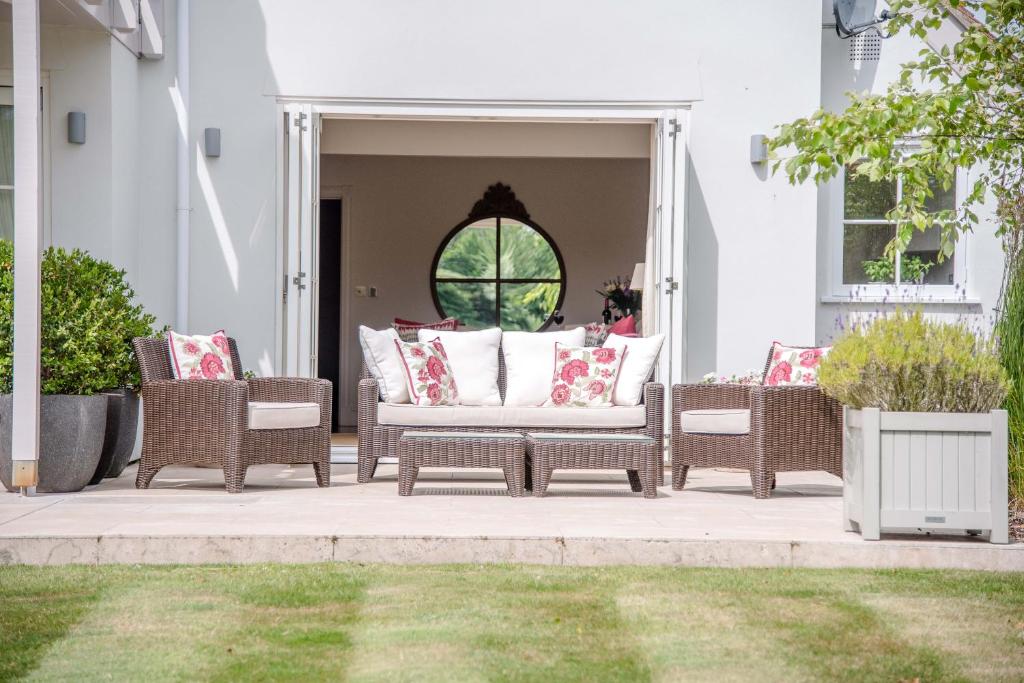 a porch with wicker chairs and pillows on it at The Lily Pad in Thorpeness