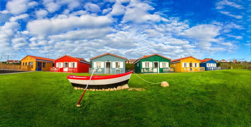 a boat on the grass in front of a row of houses at Cabanas de Vendaval in Malpica