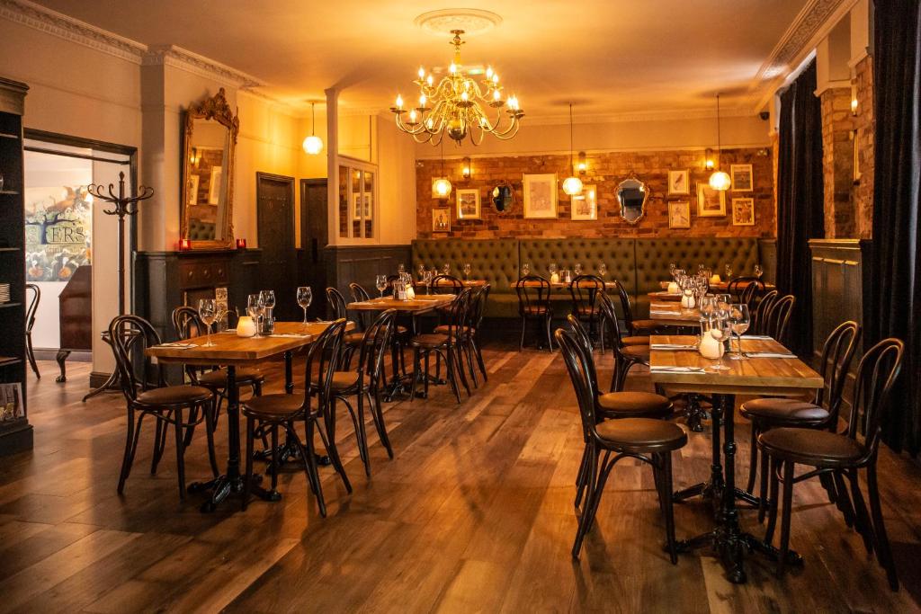 a restaurant with wooden tables and chairs and a chandelier at The Foresters Arms in Kingston upon Thames