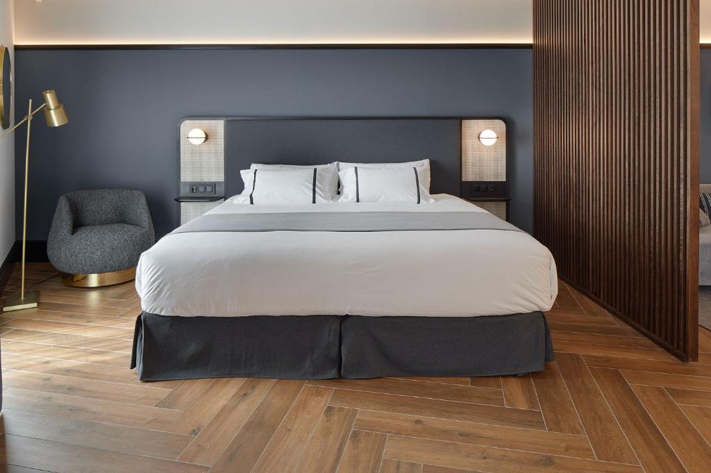 a bedroom with a large bed and a chair at Hotel SANSEbay in Donostia-San Sebastián