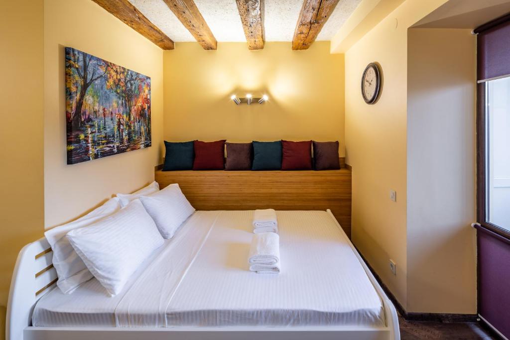 1 dormitorio con 1 cama blanca y reloj en la pared en Alfa Apartments Rynok Square 18, en Leópolis
