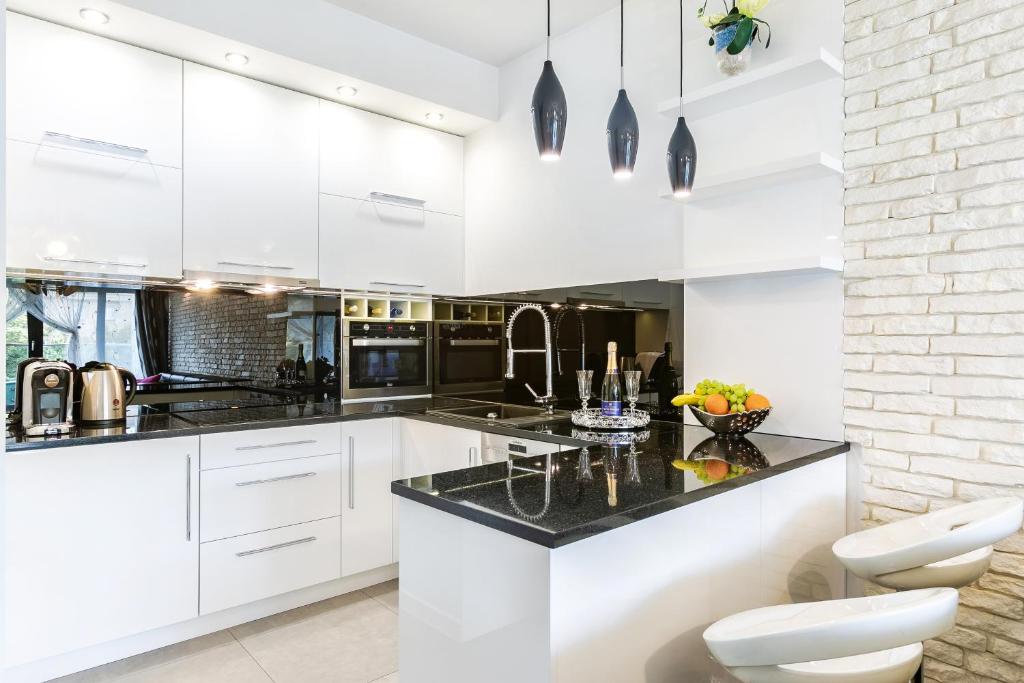 uma cozinha com armários brancos e bancadas pretas em Golden Queen Apartments Jewish District em Cracóvia