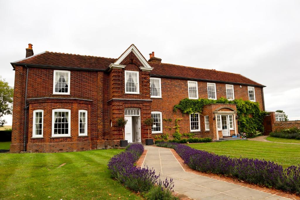 B&B Downham Hall في ويكفورد: منزل من الطوب مع الزهور الأرجوانية أمامه