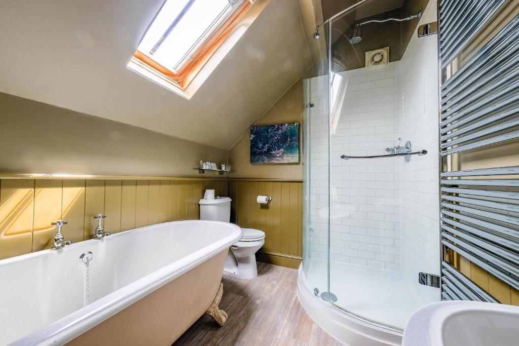 a bathroom with a tub and a toilet and a skylight at The Westleton Crown in Westleton