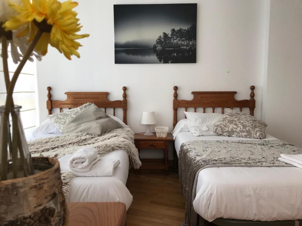 1 dormitorio con 2 camas y un jarrón con una flor en Apartamentos Arha, en Potes