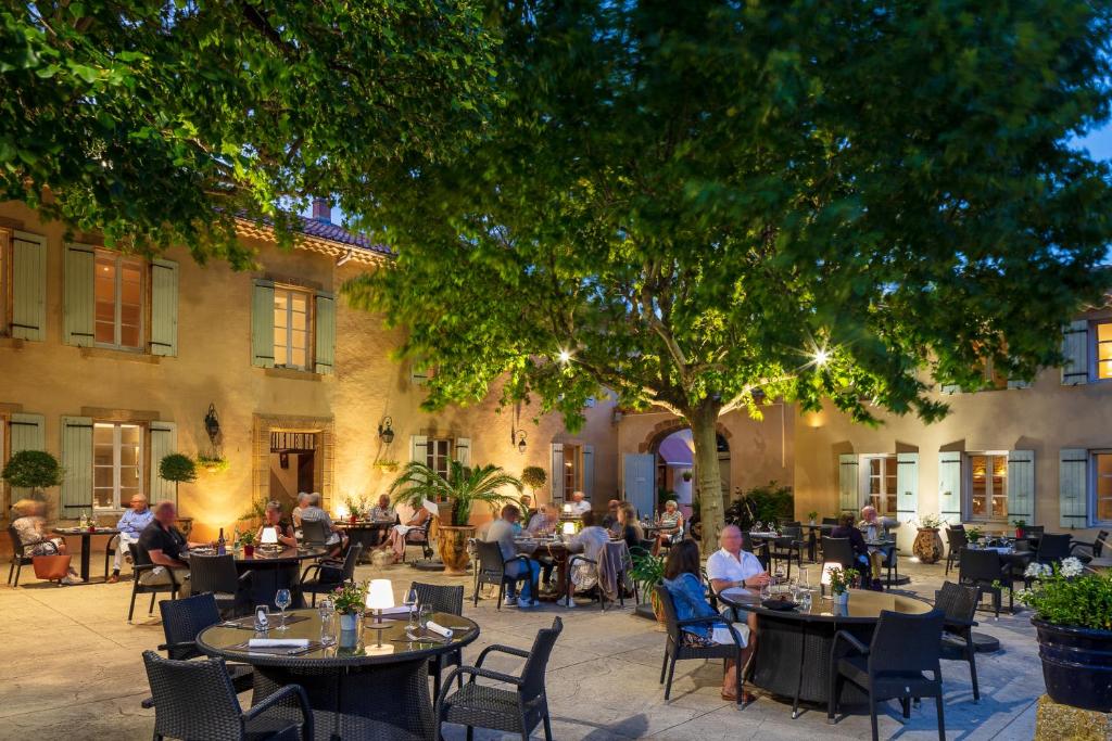 eine Gruppe von Personen, die an Tischen im Innenhof sitzen in der Unterkunft Le Pré du Moulin - Maison Alonso - Hôtel & Restaurant in Sérignan-du-Comtat