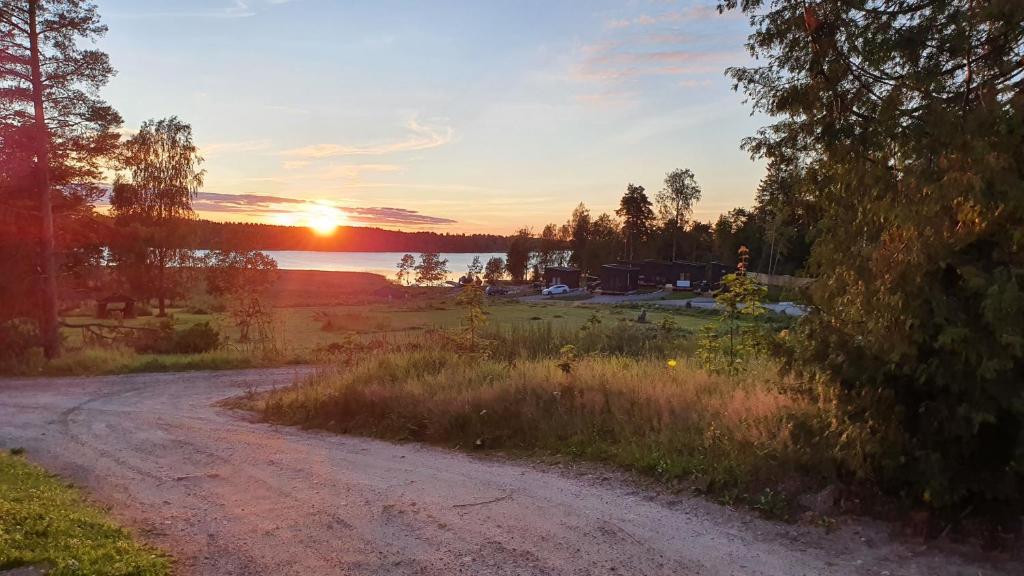 a dirt road next to a lake at sunset at Minivilla by the sea in Dragsfjärd