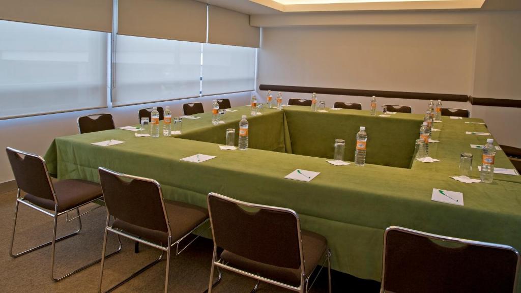 A windowed meeting room arranged in a U-shaped configuration with green tablecloths.