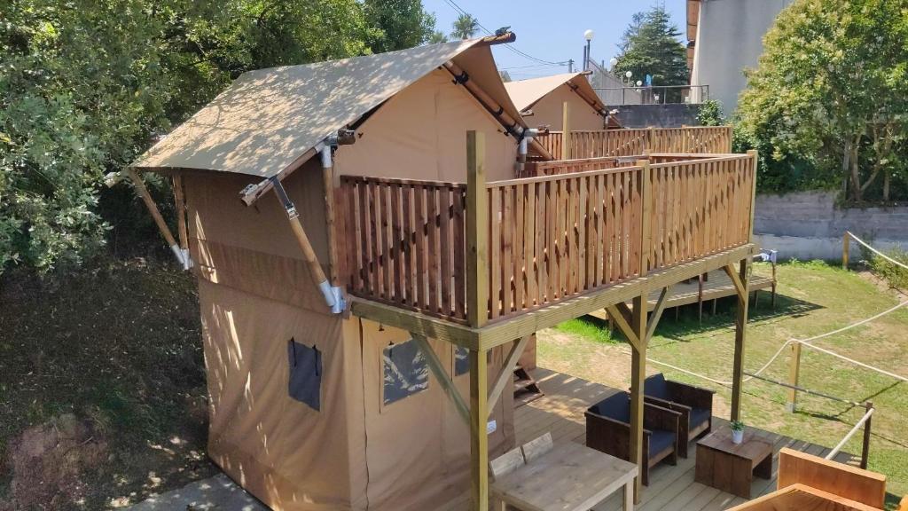 una casa de juegos con terraza de madera y escaleras en Camping Las Gaviotas, en Naveces