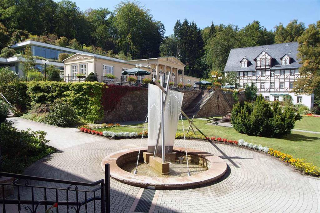 une fontaine dans un parc en face d'un bâtiment dans l'établissement Thermalbad Wiesenbad, à Thermalbad Wiesenbad