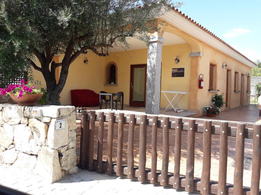 una cerca frente a una casa con un árbol en Affittacamere b&b Il FIORE, en Posada