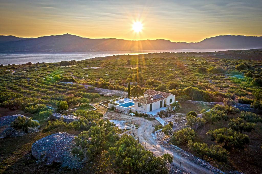 une vue aérienne sur une maison avec le coucher du soleil en arrière-plan dans l'établissement Villa Little Hill, à Postira