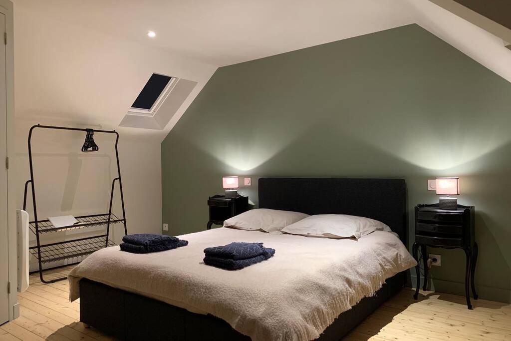 a bedroom with a large bed with two blue towels on it at Robert's Family Petite Maison de Ville in Plancoët