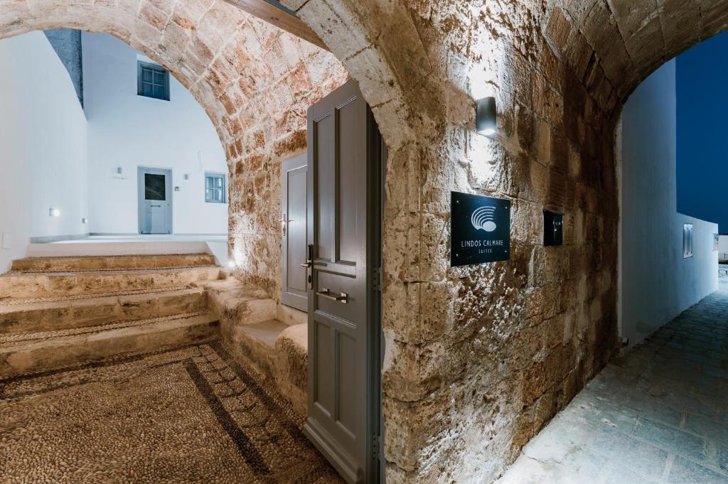 um corredor com uma porta aberta numa parede de pedra em Lindos Calmare Suites em Lindos