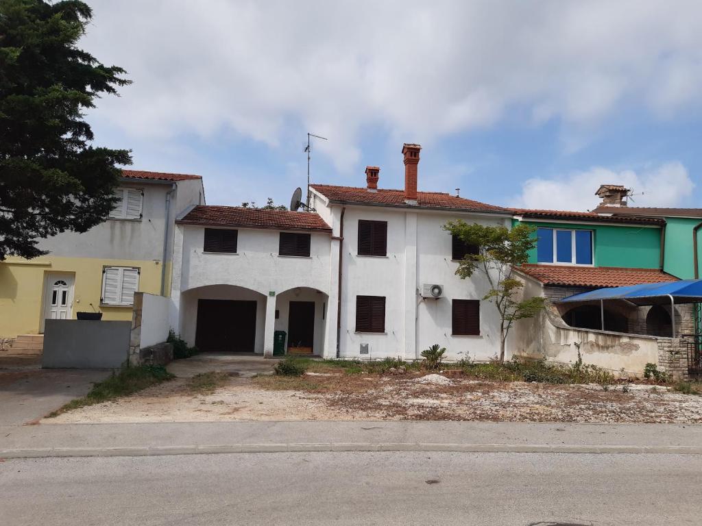 a white house with black windows on a street at Apartments Kana in Pula