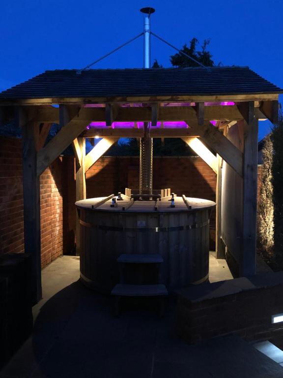 a wooden gazebo with a hot tub with purple lights at Herons Reach in Budleigh Salterton